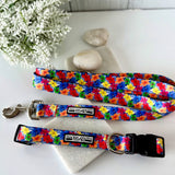 Tropical hibiscus patterned dog collar and leash set displayed on white stones with white flowers.