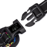 Close-up of a black plastic side-release buckle on a dog harness strap with reflective stitching.