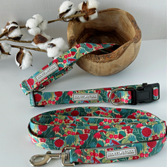 Floral-patterned dog collar and leash set on a white surface with cotton branches in the background.