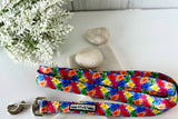 Bright blue dog leash with a colorful floral pattern, displayed with white stones and flowers.