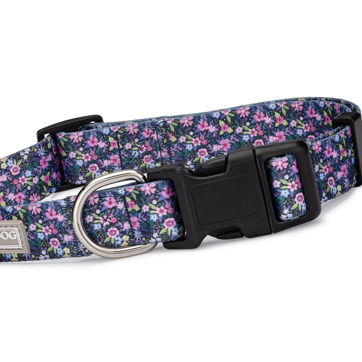 Purple floral dog collar featuring a vibrant ditsy flower pattern with a black plastic buckle and metal D-ring on a white background.