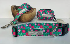 Walk in style with this vibrant teal and pink floral dog collar set by Lucky Love Dog, complete with a matching leash coiled in a wooden bowl and a cute accessory pouch for on-the-go adventures.