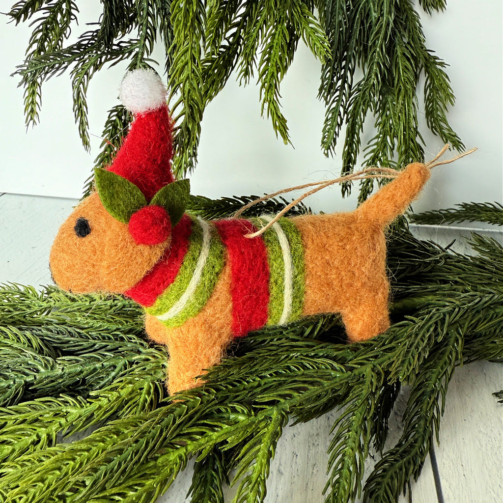 Felt dog Christmas ornament with a Santa hat and striped sweater on a pine branch