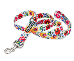 White dog leash with a vibrant red, yellow, and blue folk-art floral pattern.